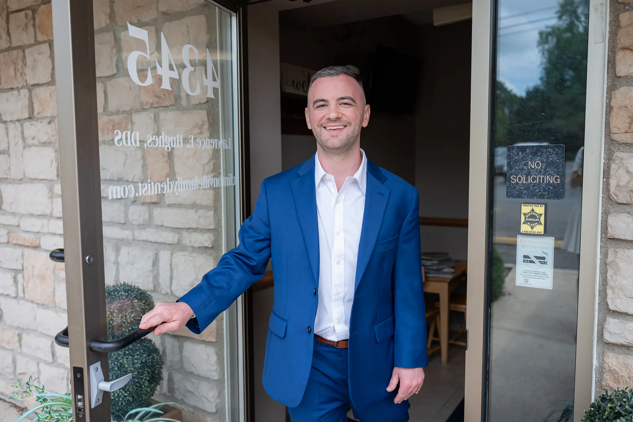 Dentist in a blue suit holding open the door at 4345 N High St