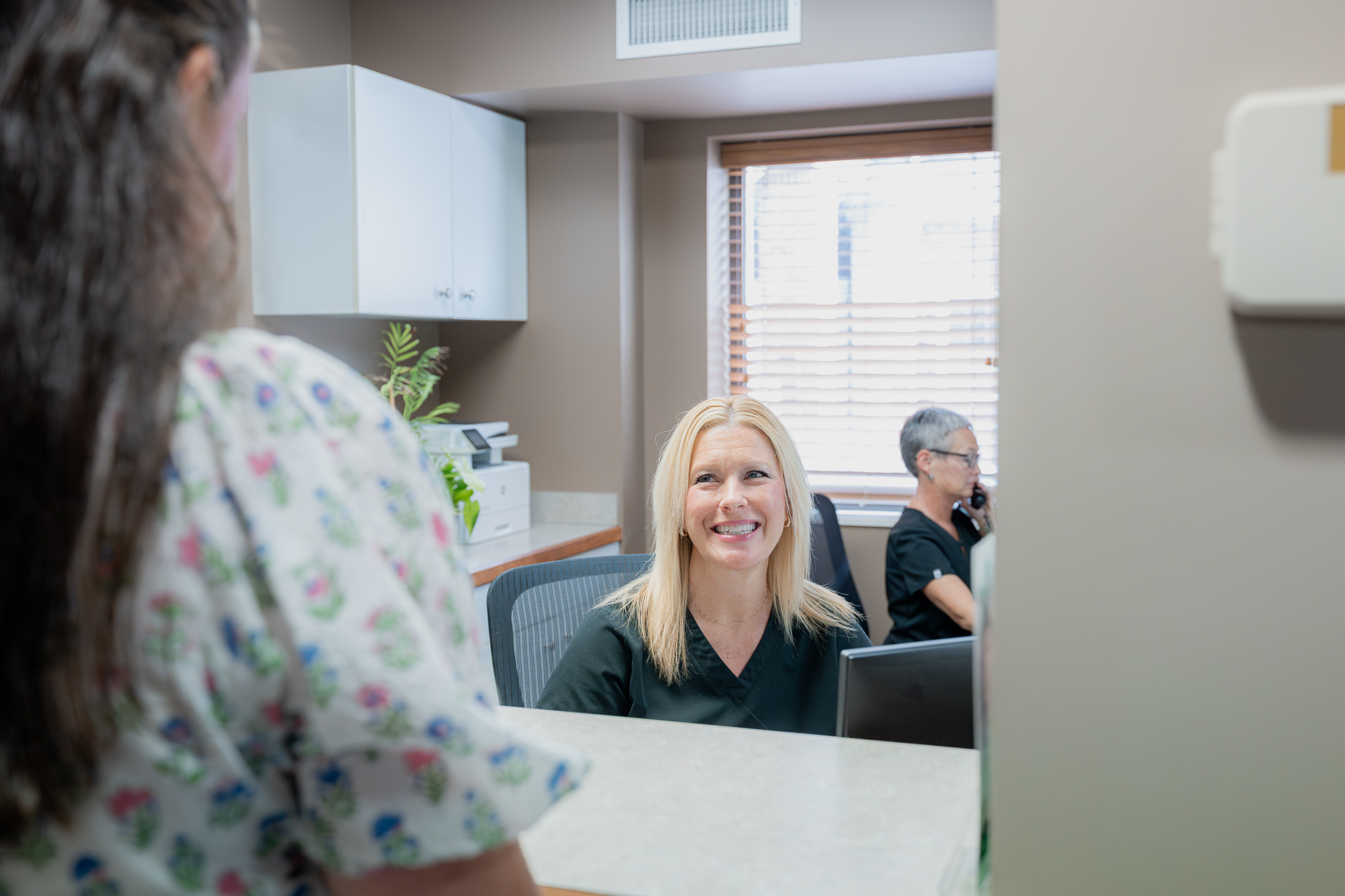 Smiling front desk team member welcoming a patient at reception