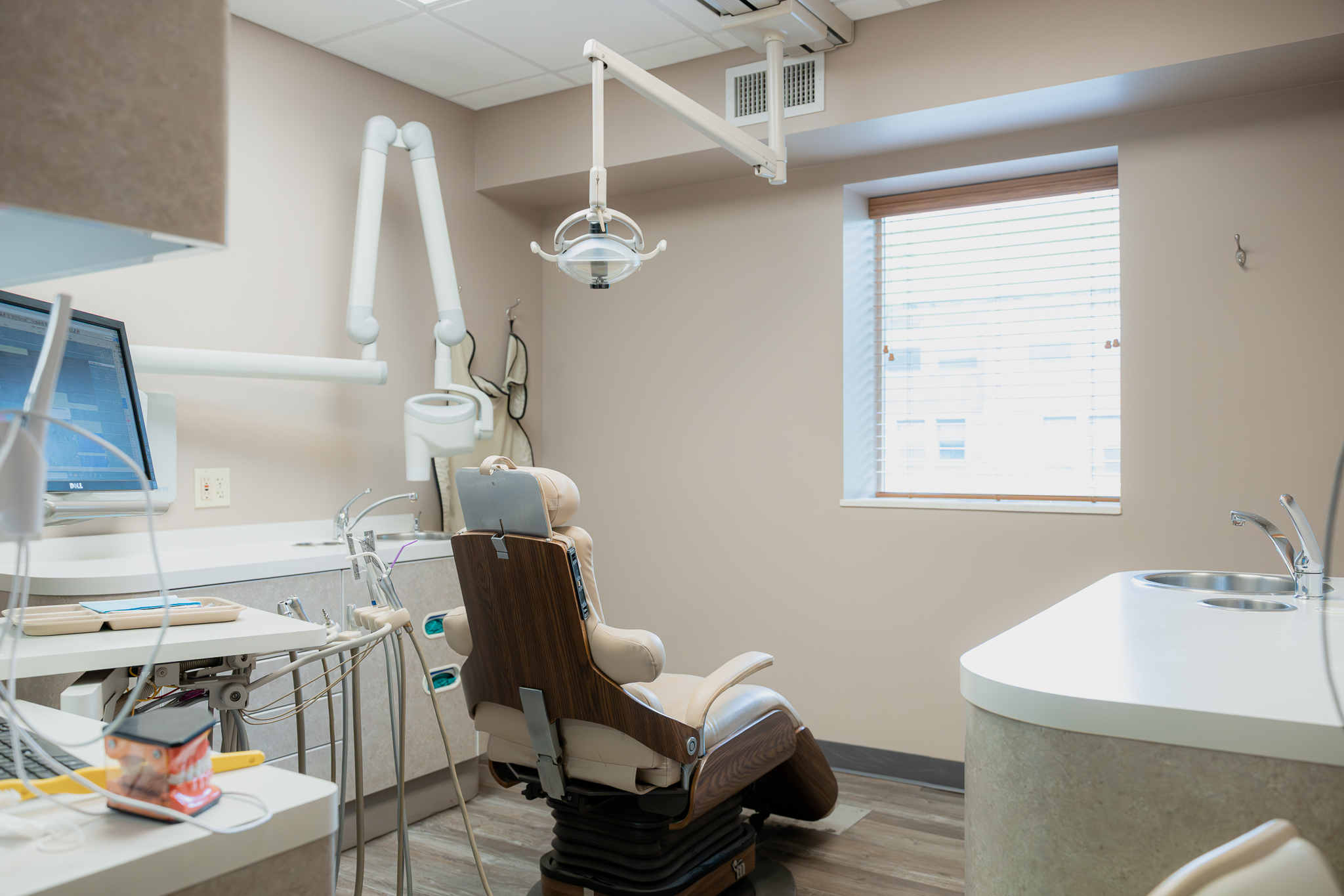 Treatment room with a dental chair, overhead light and monitor
