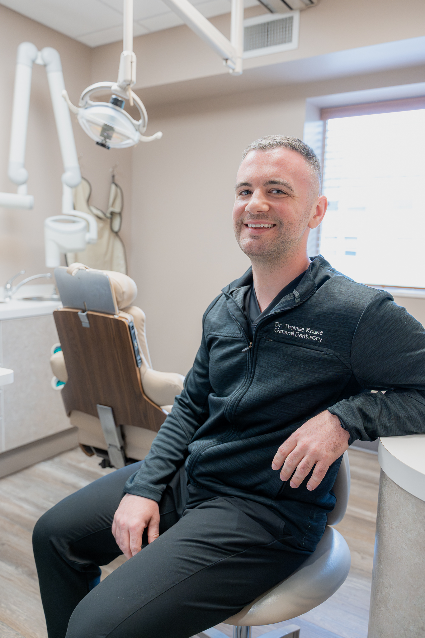 Dr. Thomas Rouse, DDS, seated in a treatment room beside the dental chair