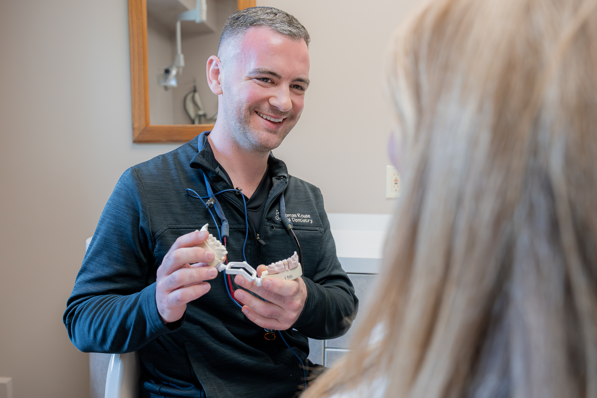 Dr. Thomas Rouse holding a dental model while talking with a patient