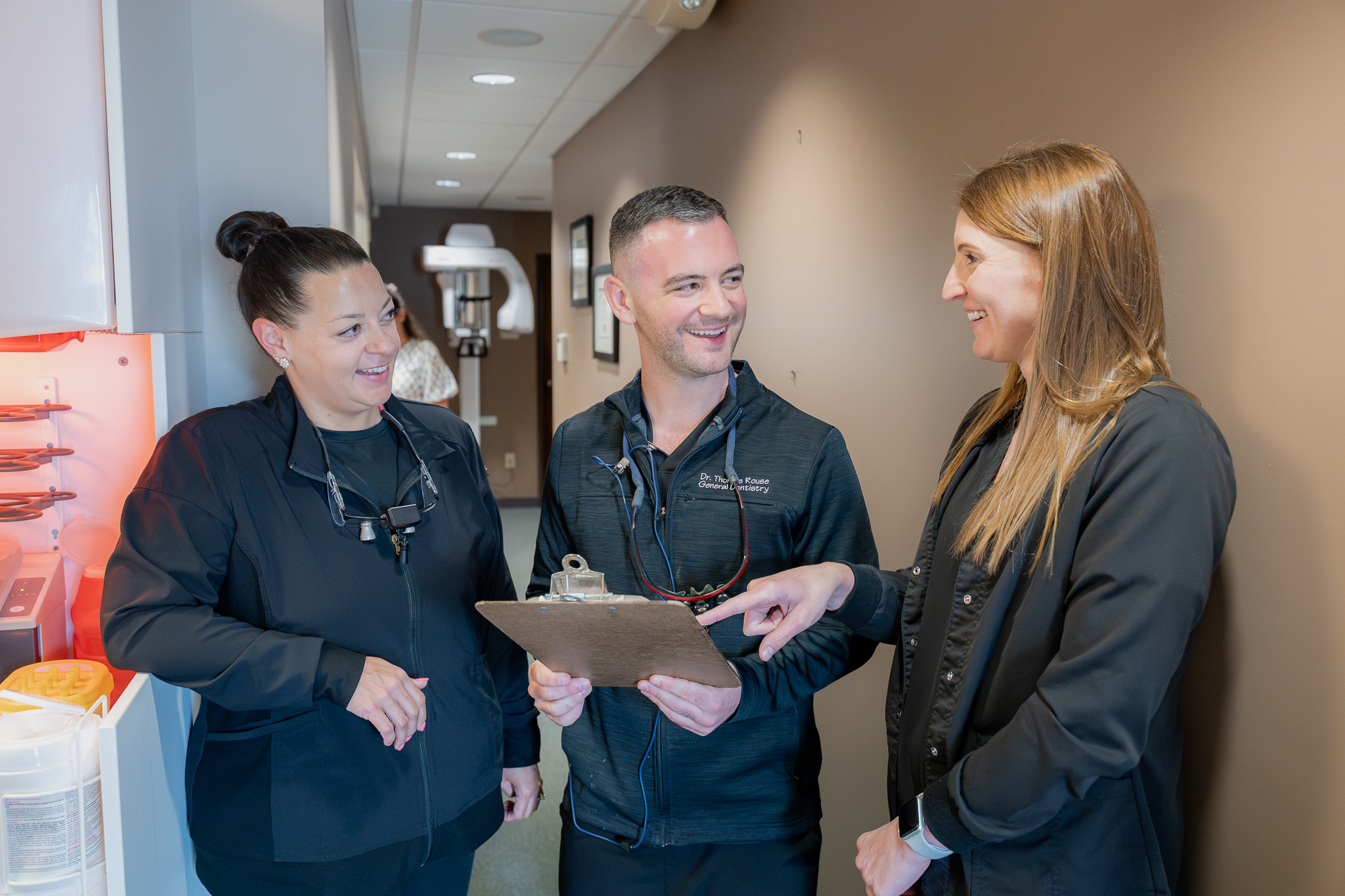 Dr. Thomas Rouse reviewing a clipboard with two team members in the hallway